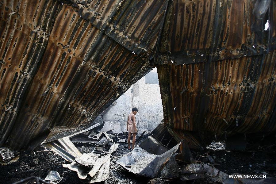 A boy looks for reuseable materials at his charred home after a fire hit a residential area in Valenzuela City, the Philippines, Feb. 19, 2013. Around 500 houses were razed in the fire, leaving 2,000 residents homeless. (Xinhua/Rouelle Umali) 