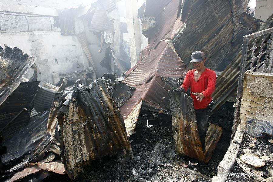 A man looks for reuseable materials at his charred home after a fire hit a residential area in Valenzuela City, the Philippines, Feb. 19, 2013. Around 500 houses were razed in the fire, leaving 2,000 residents homeless. (Xinhua/Rouelle Umali) 