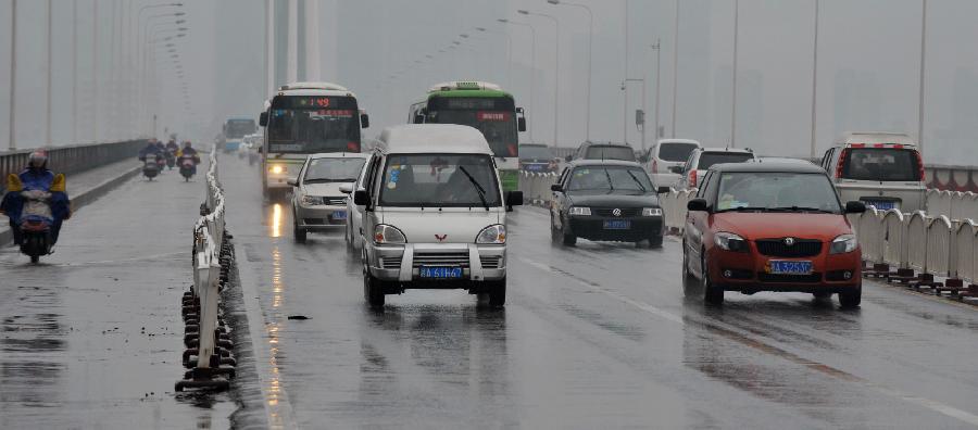 Vehicles run on a road in Changsha, capital of central China's Hunan Province, Feb. 20, 2013. Heavy fog shrouded Changsha due to a temperature drop on Wednesday, disturbing the city's traffic. (Xinhua/Long Hongtao)