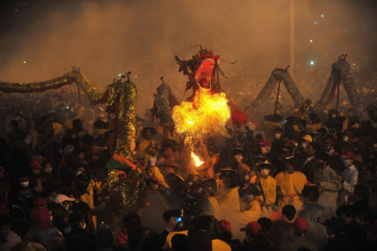 People perform a dragon dance among the fireworks in downtown Bingyang county in South China's Guangxi Zhuang autonomous region on Feb 20, 2013. The county celebrates its annual traditional dragon dance and firework festival on Jan 11 of the Chinese lunar calendar. (Photo/Xinhua) 