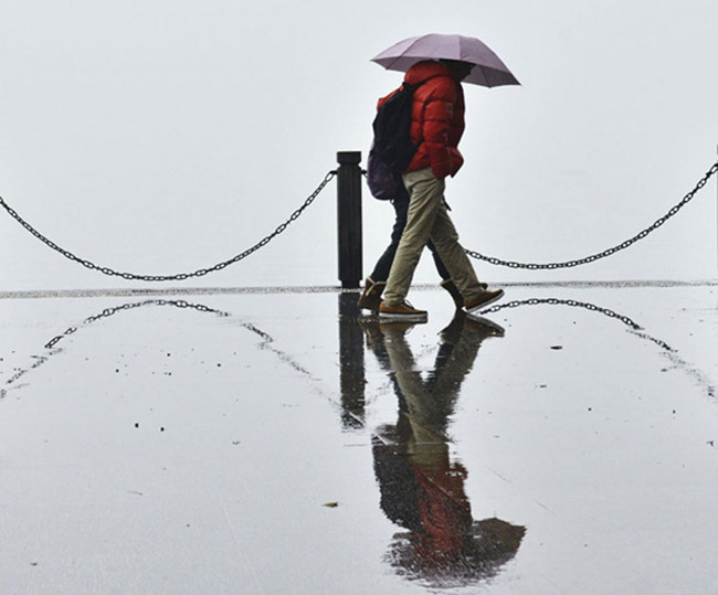 Tourists play and walk in rain at West Lake in Hangzhou on Feb. 18, 2013. The first rain came on Rain Water, the second solar term. (Photo/Xinhua)