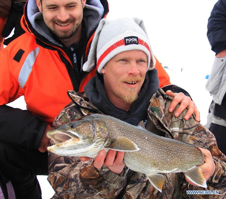 Everson (R) poses for photos with a lake trout that he caught during the 19th Canadian Ice Fishing Championship on Lake Simco at Jackson's Point, Town of Georgina, Ontario, Canada, Feb. 24, 2013. The two-day competition kicked off on Saturday and attracted 96 anglers from the country and the United States. (Xinhua/Zou Zheng)