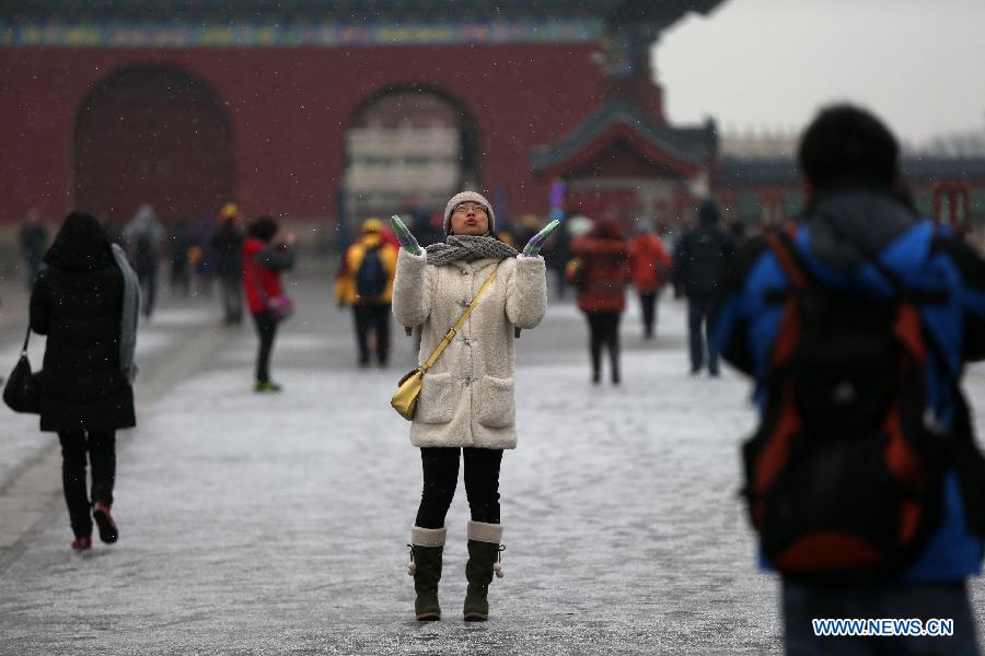 A citizen poses for photos in snow at the Temple of Heaven Park in Beijing, capital of China, Feb. 25, 2013. Beijing received snowfall on Monday. (Xinhua/Jin Liwang) 