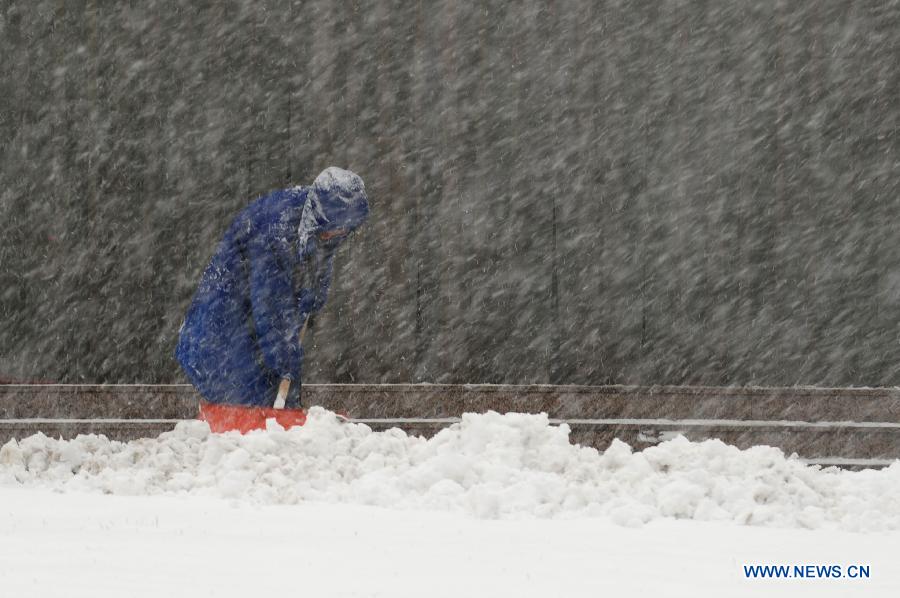 A metro staff member removes snow at the exit of a metro station in Shenyang, capital of northeast China's Liaoning Province, Feb. 28, 2013. Liaoning was hit by a snowstorm on Thursday. (Xinhua/Pan Yulong)