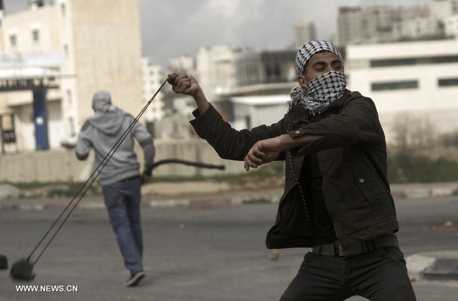 Palestinian protesters hurl stones at Israeli soldiers outside Ofer Prison near Ramallah on Feb. 28, 2013, following a protest supporting Palestinian prisoners. Israeli troops arrested 3 protesters and 19 were reportedly injured. (Xinhua/Fadi Arouri)