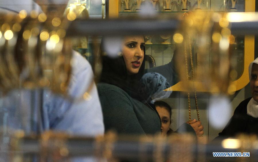 A Palestinian woman picks Russian gold products at a gold market in the West Bank city of Nablus on March 2, 2013. (Xinhua/Ayman Nobani)