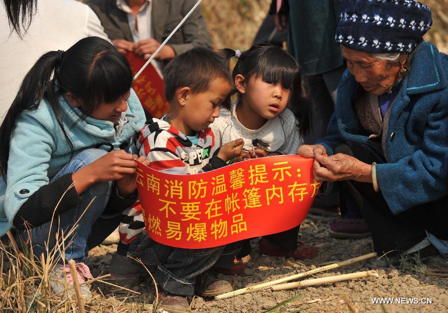 People receive a poster warning against storing explosives in tents at Qiandian Village of Liantie Township in Eryuan County of Dali Bai Autonomous Prefecture, southwest China's Yunnan Province, March 4, 2013. A 5.5-magnitude earthquake hit Eryuan County on March 3. Thirty people have been confirmed injured, while some 21,000 people have been evacuated. (Xinhua/Lin Yiguang) 