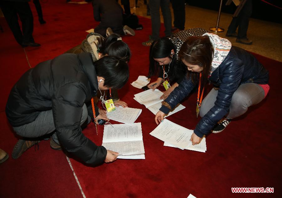 Journalists read conference materials on the floor of the Great Hall of the People in Beijing, capital of China, March 5, 2013. The first session of the 12th National People's Congress (NPC) will open here on March 5. (Xinhua/Chen Jianli)