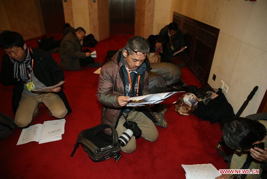 Journalists read conference materials on the floor of the Great Hall of the People in Beijing, capital of China, March 5, 2013. The first session of the 12th National People's Congress (NPC) will open here on March 5. (Xinhua/Chen Jianli)