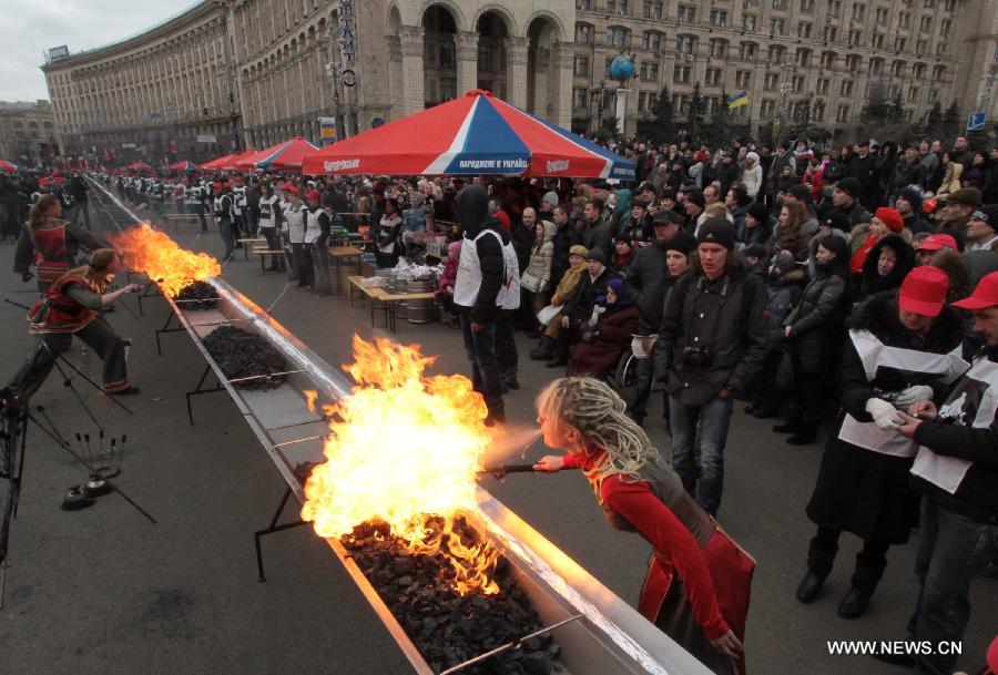 A girl sets fire to charcoal before grilling shish kebab in Kiev, Ukraine, March 2, 2013. A 150.6-meter-long kebab was made in Kiev on Saturday. A total of 200 kg of meat and 800 kg of charcoal were used to make the kebab.(Xinhua/Sergey Starostenko) 