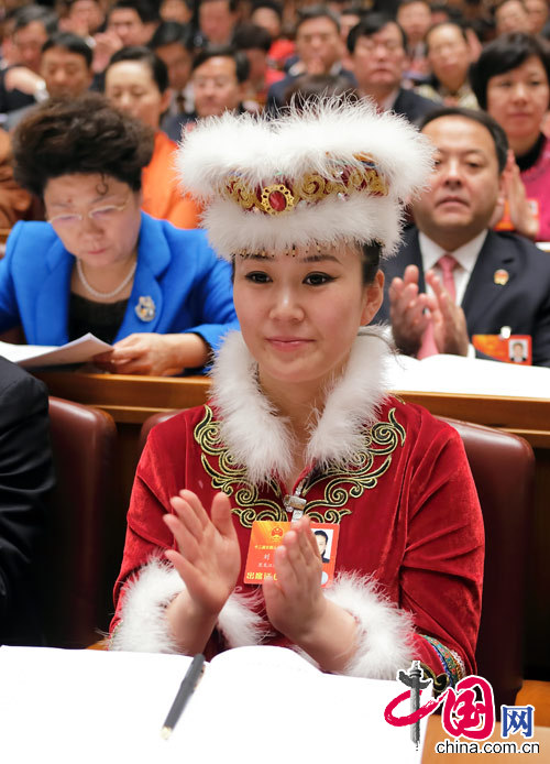 A female ethnic minority deputy wearing a traditional ethnic minority costume carefully listens the government work report during the opening meeting of the first session of the 12th National People's Congress (NPC) at the Great Hall of the People in Beijing, capital of China, March 5, 2013. (China Pictorial/Xu Xun)