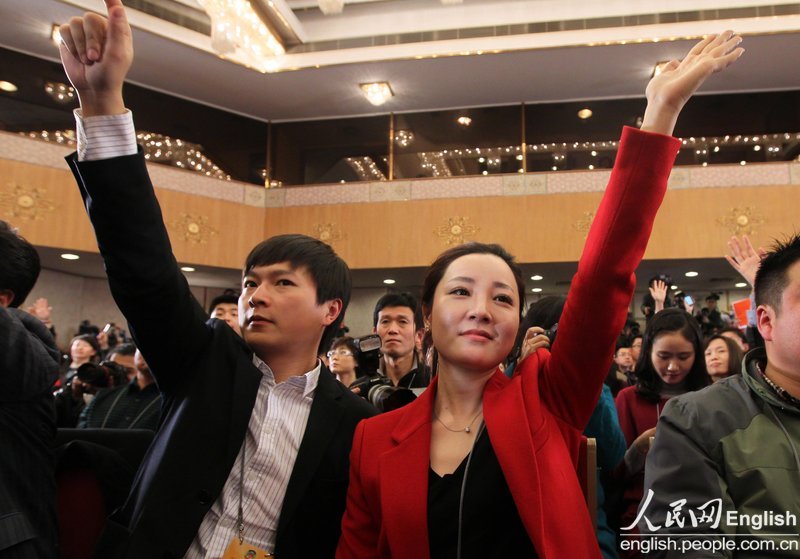 Two journalists raise their hands to ask questions during the press conference of 12th CPPCC National Committee on March 02, 2013. (Photo/ People's Daily Online)