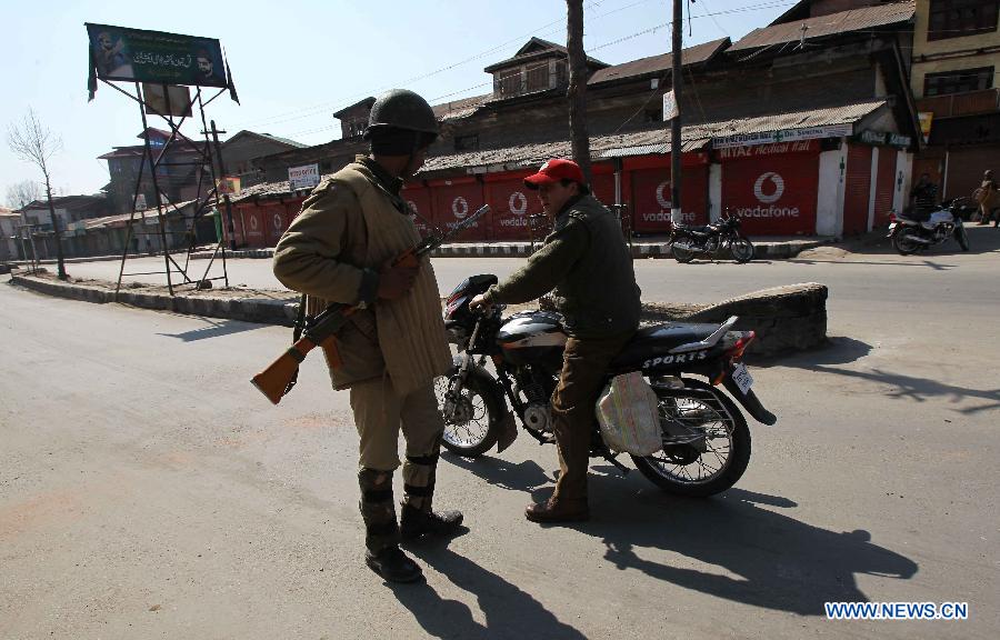 An Indian paramilitary soldier stops a man on motorcycle during curfew in Srinagar, summer capital of Indian-controlled Kashmir, March 6, 2013. Indian army troopers on Tuesday killed a young man and wounded another after opening gunfire at protesters in Indian-controlled Kashmir, officials said. (Xinhua/Javed Dar)