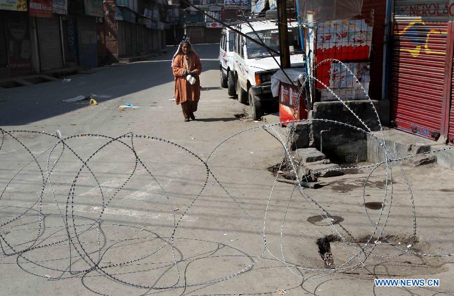 A Kashmiri woman carries milk packets as she walks past a barbed wire during curfew in Srinagar, summer capital of Indian-controlled Kashmir, March 6, 2013. Indian army troopers on Tuesday killed a young man and wounded another after opening gunfire at protesters in Indian-controlled Kashmir, officials said. (Xinhua/Javed Dar)