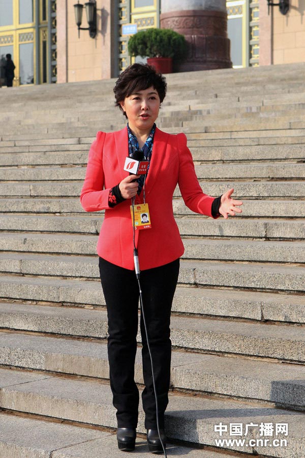 A television host wearing red suit reports at Tiananmen Square. (Photo/www.cnr.cn) 