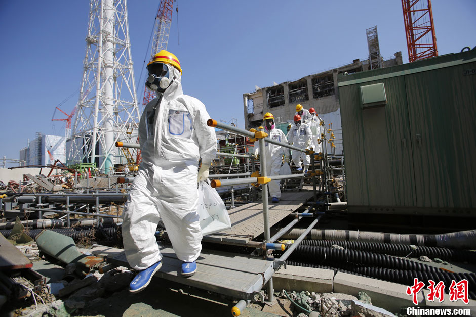 Workers stand near the multi-nuclide removal facility being constructed at Tokyo Electric Power Co.'s tsunami-crippled Fukushima Dai-ichi nuclear power plant in Okuma, Fukushima prefecture, Wednesday, March 6, 2013, ahead of the second anniversary of the March 11 earthquake and tsunami. Some 110,000 people living around the nuclear plant were evacuated after the massive disasters knocked out the plant's power and cooling systems, causing meltdowns in three reactors and spewing radiation into the surrounding air, soil and water. (Chinanews.com)