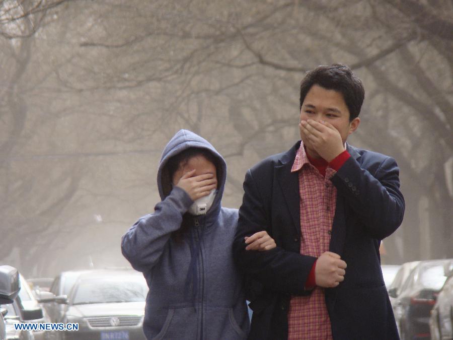 Two pedestrians cover their mouths while braving wind and sand on a street in Beijing, capital of China, March 9, 2013. A cold front brought strong wind as well as sand and dust to most part of north China region on March 9. (Xinhua/He Huaqiao) 