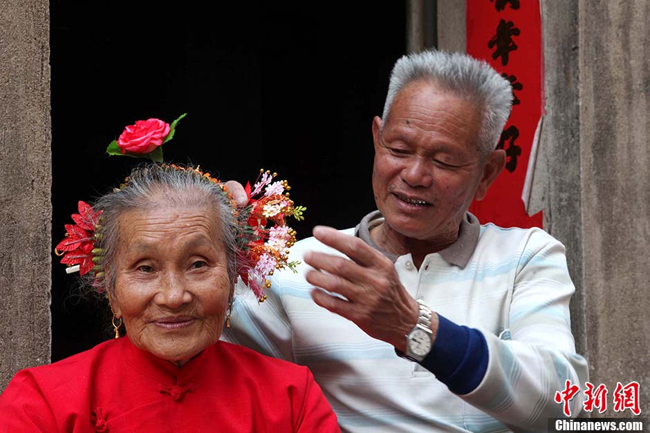 Zheng Xiya, 78, helps his wife put flowers in her hair, to celebrate the folk festival honoring the sea goddess Mazu in Xunpu village, Hui’an city of East China’s Fujian province, March 10, 2013. (Photo/CNS)