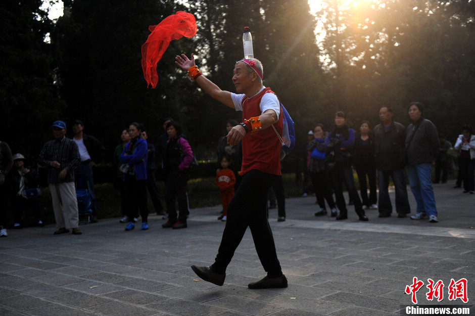 Yang Lesheng, 71, was a zookeeper before retirement. For a moment, he suffered from cervical spondylosis, so he created a dance to practice the neck by putting a bottle on the head. He also made the costume especially for the dance. (Chinanews/Li Meiduo)