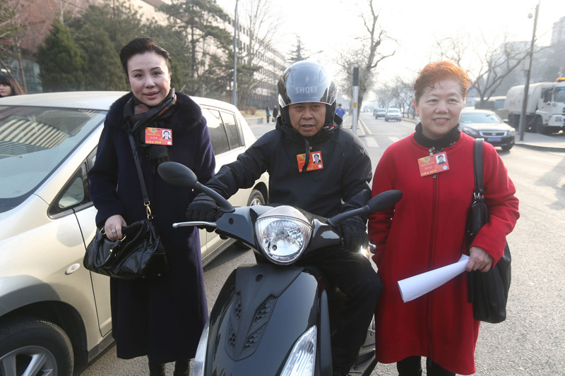 Members of CPPCC National Committee Zhao Xiujun, Gao Peifen, Zuo Zongshen (from left to right) pose for a photo at Xuanwumen before departure. (Xinhua/Xing Guangli)