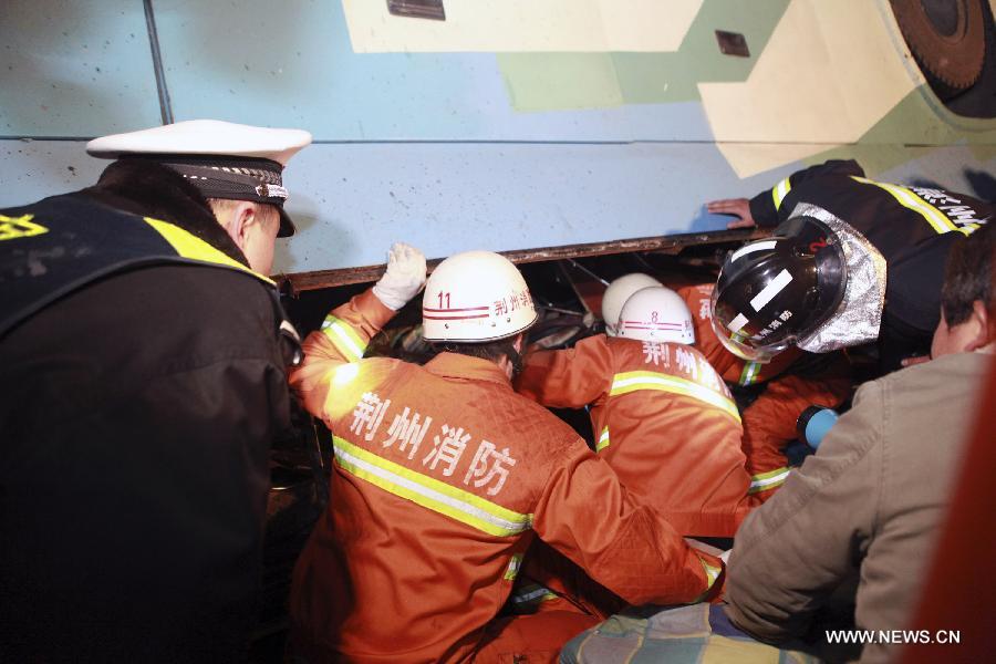 Rescuers search for victims at the accident site after a sleeper coach fell off the Jingzhou Yangtze River Bridge in Jingzhou, central China's Hubei Province, March 12, 2013. At least 14 people were killed and nine injured during the the accident which happened at around 7:00 p.m. Tuesday when a flat tire caused the coach to break through the guardrail at the southern end of the bridge and hit the ground underneath the structure. Rescue work is under way. (Xinhua/Shi Jiuyong)   