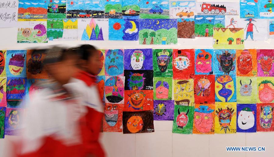 Pupils of the Tibetan ethnic group walk past the painting works of their schoolmates at No. 1 Primary School of Deqin County in Diqing Tibetan Autonomous Prefecture, southwest China's Yunnan Province, March 12, 2013. A total of 1,260 pupils, most of whom are of the Tibetan ethnic group, study at this school, which was founded in September 2012. Pupils here are offered free meals and lodging. (Xinhua/Lin Yiguang) 