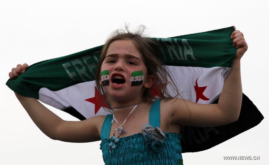 A Syrian girl living in Jordan holds Syrian revolutionary flags and shouts slogans against President Bashar al-Assad during a rally in front of the Syrian embassy in Amman, Jordan, March 15, 2013. Hundreds gathered in front of the Syrian embassy to mark the second anniversary of the start of the conflict against the regime of Al-Assad. (Xinhua/Mohammad Abu Ghosh)