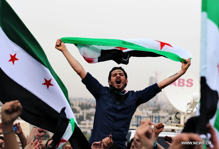 Syrian men living in Jordan hold Syrian revolutionary flags and shout slogans against President Bashar al-Assad during a rally in front of the Syrian embassy in Amman, Jordan, March 15, 2013. Hundreds gathered in front of the Syrian embassy to mark the second anniversary of the start of the conflict against the regime of Al-Assad. (Xinhua/Mohammad Abu Ghosh) 