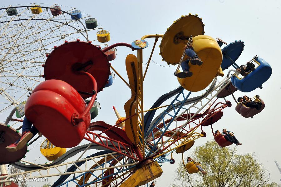 Citizens play at an amusement park during the early Spring in Jinan City, capital of east China's Shandong Province, March 16, 2013. (Xinhua/Guo Xulei)  