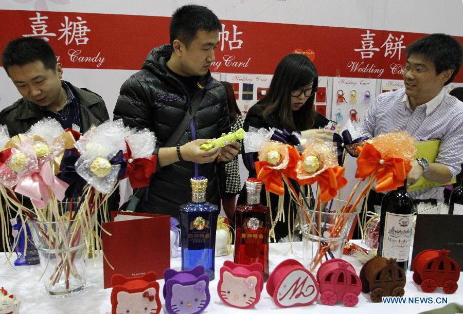 Visitors look at wedding candies during the 2013 Xici Wedding Expo for Spring in Nanjing, capital of east China's Jiangsu Province, March 16, 2013. Most of the exhibitors possess both physical stores and online shops, attracting many net users to the expo which will last to March 17. (Xinhua/Dong Jinlin)