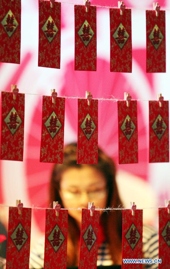 A woman looks at wedding items presented during the 2013 Xici Wedding Expo for Spring in Nanjing, capital of east China's Jiangsu Province, March 16, 2013. Most of the exhibitors possess both physical stores and online shops, attracting many net users to the expo which will last to March 17. (Xinhua/Yan Minhang) 