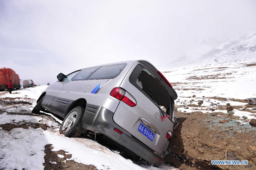 A van overturns on the segment of state highway 109 which is covered with snow near Nalong Village in Damxung County, southwest China's Tibet Autonomous Region, March 18, 2013. A snowstorm here made an icy road on the segement of state highway 109 near Nalong Village, causing many vehicles truck on the road. (Xinhua/Liu Kun)