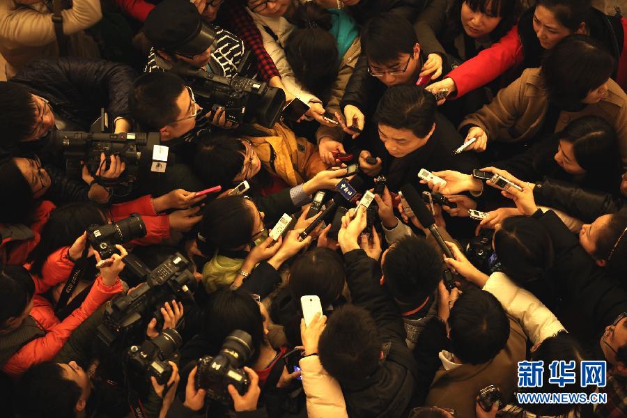 Cui Yongyuan, a famous talk show host, is bombarded with journalists’ questions after the opening of the first session of 12th CPPCC National Committee.  (Xinhua/ Jin Liwang)
