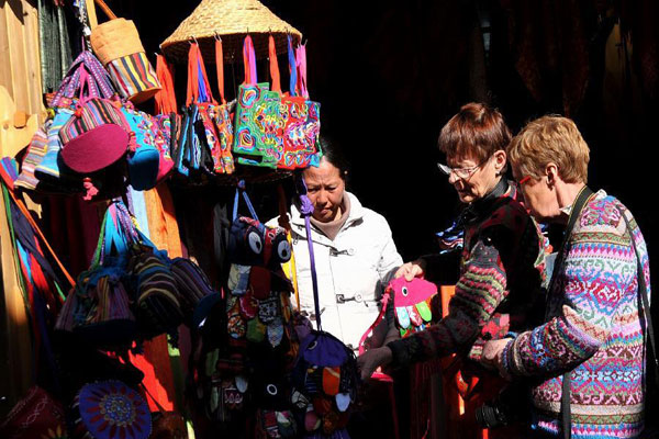 Two foreign tourists are choosing ethnic handicrafts in the "Dukezong" Ancient Town. [Photo/Xinhua] 
