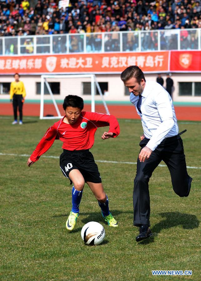British soccer player David Beckham (R) plays soccer with students at the Qingdao Tiantai Stadium in Qingdao, east China's Shandong Province, March 22, 2013. Beckham visited Qingdao Jonoon Soccer Club as the ambassador for the youth football program in China and the Chinese Super League Friday. (Xinhua/Li Ziheng)