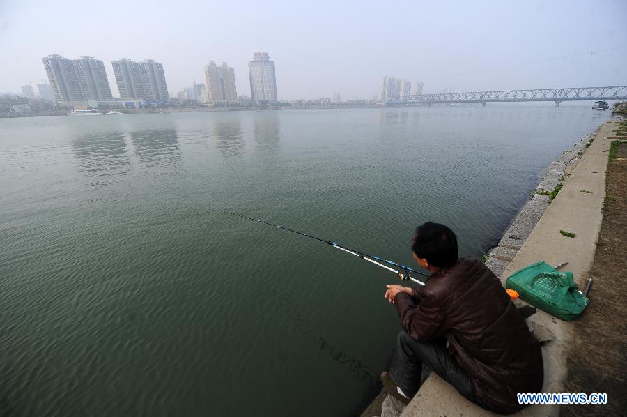 A citizen fishes on the bank of the Hanjiang River under the old city wall in Xiangyang, central China's Hubei Province, March 21, 2013. (Xinhua/Li Xiaoguo)