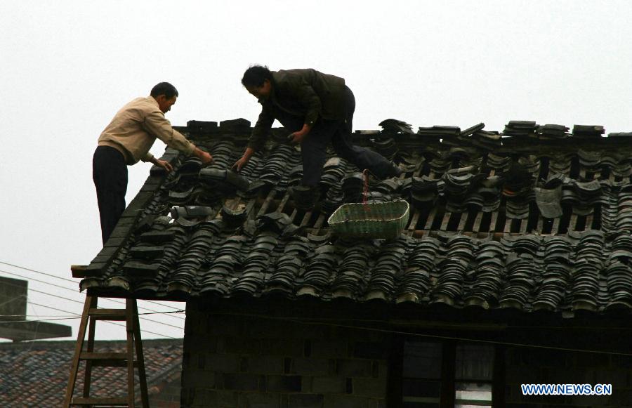 Villagers repairs roof at Shuangxi Village of Shuangxi Township in Jing'an County, east China's Jiangxi Province, March 23, 2013. Heavy rainfall and hailstorm battered the county Friday, causing severe waterlogging. In the havoc, gales and hailstorms damaged 5,700 houses, affecting more than 26,780 people.(Xinhua/Xu Zhongting) 