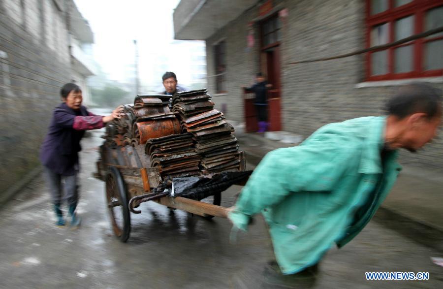Villagers carry tiles to repair roof at Shuangxi Village of Shuangxi Township in Jing'an County, east China's Jiangxi Province, March 23, 2013. Heavy rainfall and hailstorm battered the county Friday, causing severe waterlogging. In the havoc, gales and hailstorms damaged 5,700 houses, affecting more than 26,780 people.(Xinhua/Xu Zhongting) 