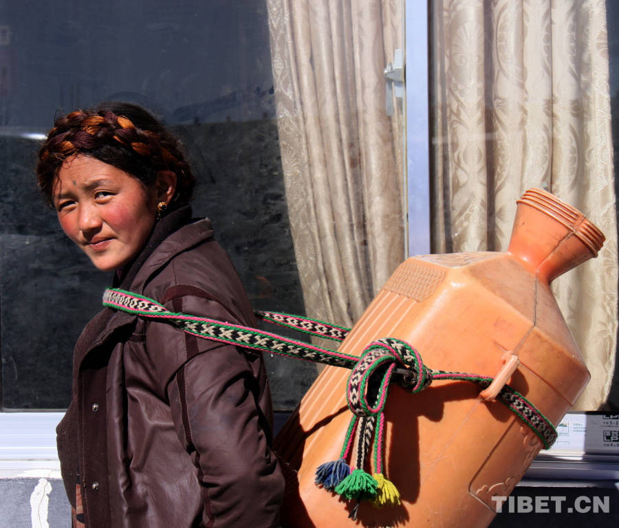 A Tibetan woman carries water. (Photo by Xi Qin)