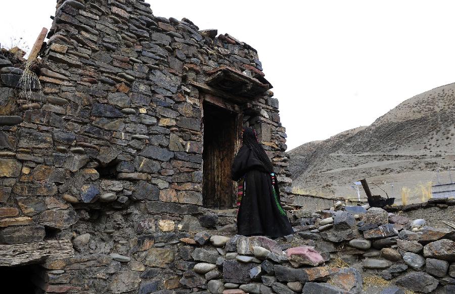 A hostess walks into a stone house which is aged over 600 years in Yangda Village of Riwar Township in Suoxian County in the Nagqu Prefecture, southwest China's Tibet Autonomous Region. Three stone houses, each with the age exceeding more than 600 years, are preserved well in the village. (Xinhua/Liu Kun) 