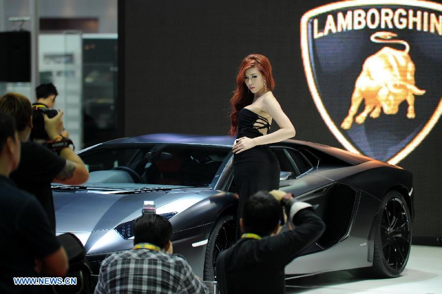 Visitors take photo of a model as she standing beside a Lamborghini roadster during the press preview of the 34th Bangkok International Motor Show in Bangkok, Thailand, on March 26, 2013. The 34th Bangkok International Motor Show will be held from March 27 to April 7. (Xinhua/Gao Jianjun)  