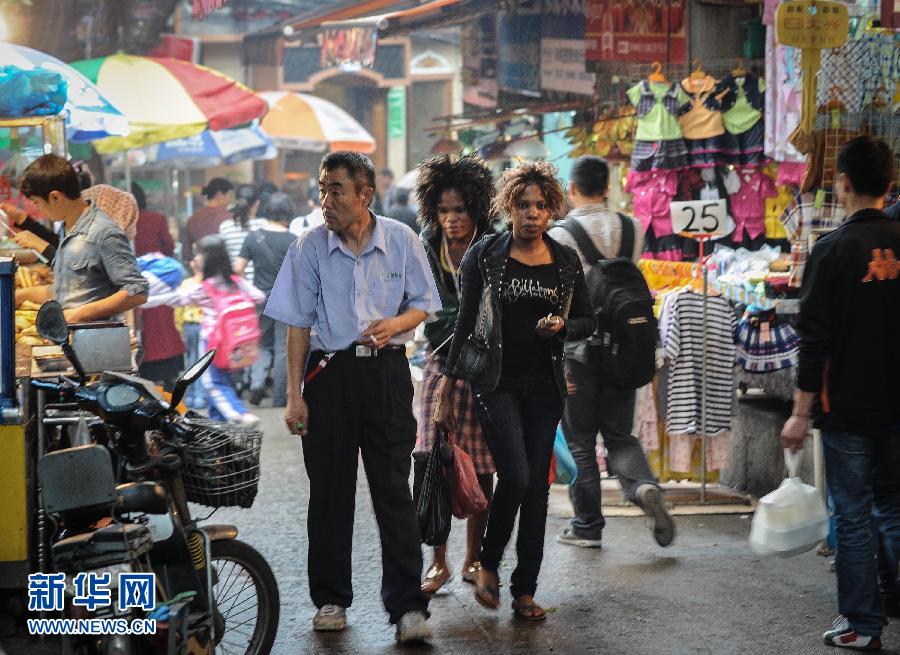 Africans and local residents walk through stalls in Guangzhou on March 21, 2013. (Xinhua/ Liu Dawei)