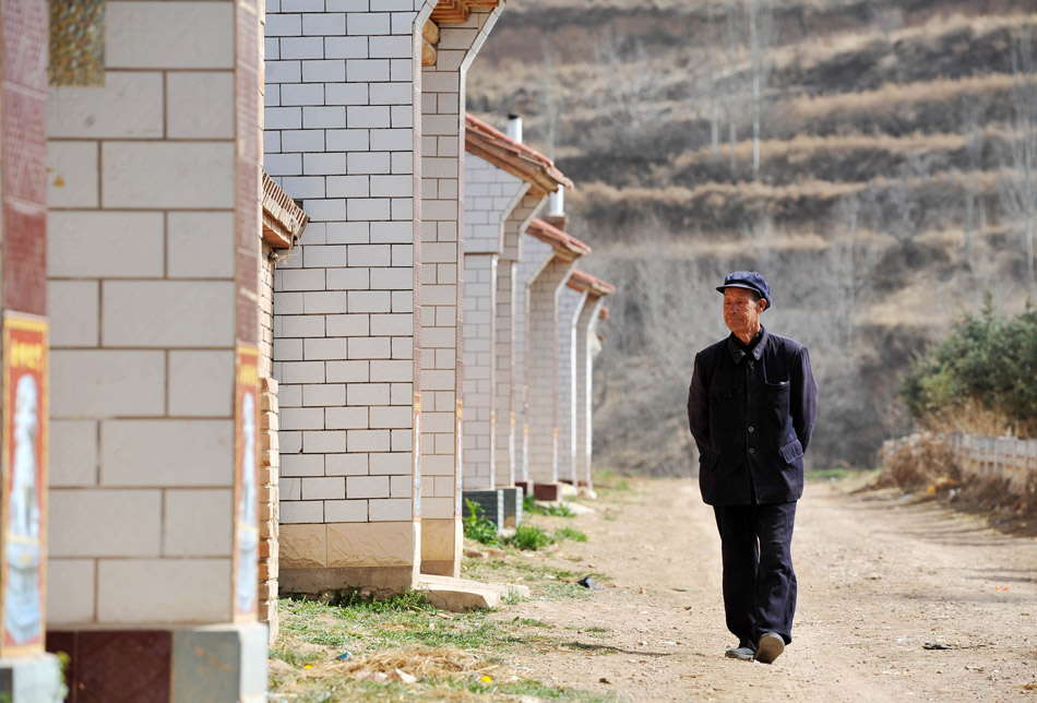 Yang Youchun, 67, strolls in the village to find someone to talk to on March 24, 2013. There were 198 families in Yangchuan village in Longde county of Ningxia Hui autonomous region, and most villagers have moved out, with only 14 villagers still living here. They can hardly find someone to talk to. (Photo/Peng Zhaoran)