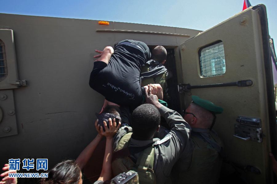 Israeli soldiers try to push a foreign protester into a car in a village near Hebron city of West Bank. (Xinhua/AFP)
