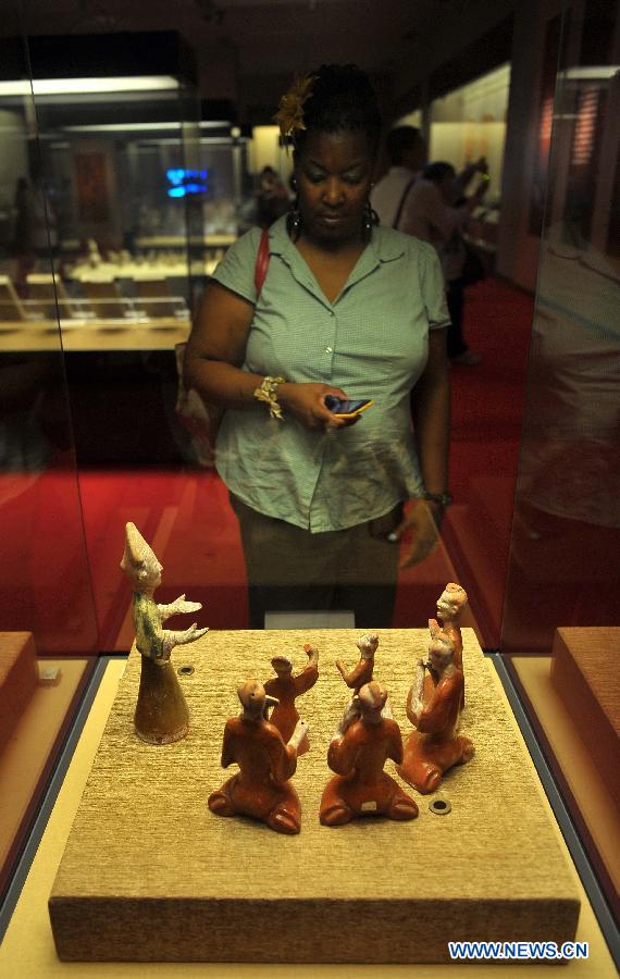 A visitor looks at the figures presented during an exhibition for antiques of ancient music at Hainan Museum in Haikou, capital of south China's Hainan Province, April 2, 2013. A total of 168 pieces of musical antiques unearthed from central China's Henan Province were on display. (Xinhua/Guo Cheng)