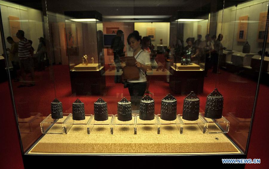 Visitors look at the items presented during an exhibition for antiques of ancient music at Hainan Museum in Haikou, capital of south China's Hainan Province, April 2, 2013. A total of 168 pieces of musical antiques unearthed from central China's Henan Province were on display. (Xinhua/Guo Cheng)