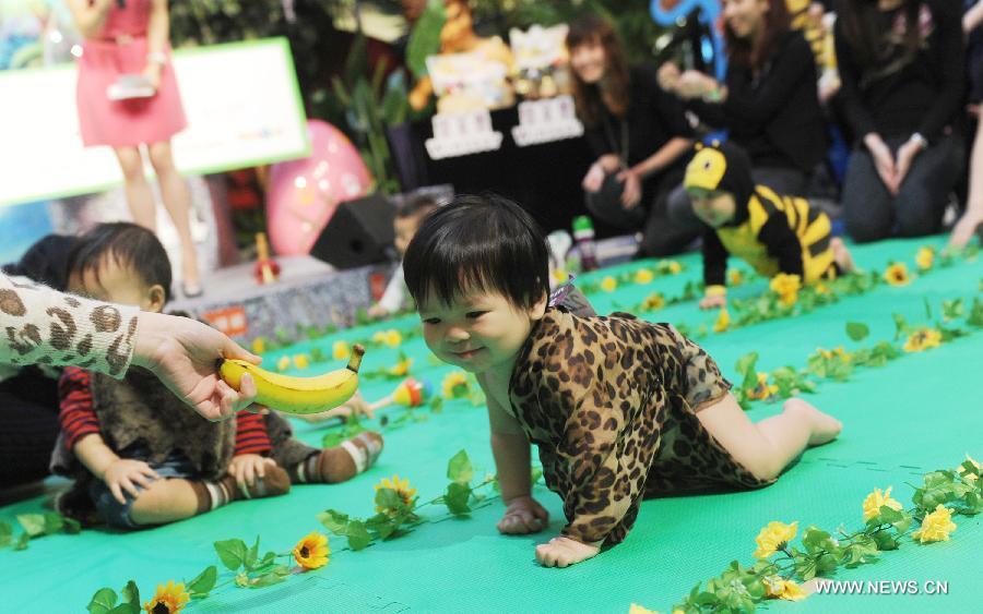 A kid crawls forward on the lure of a banana during a crawl competition held in a shopping mall in Hong Kong, south China, April 4, 2013. Many parents took their children to the event here on Thursday. (Xinhua/Lui Siu Wai)