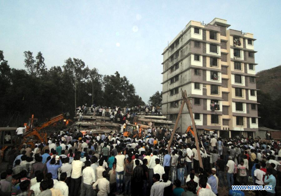 People gather as rescuers look for trapped people after a building collapsed in Thane, Mumbai, India, April 4, 2013. At least 9 people died and over 40 people were injured when an under-construction residential building collapsed on Thursday evening, local media reported. (Xinhua/Stringer) 