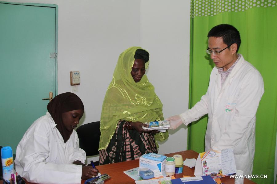 A Chinese doctor (R) gives free medication to a patient at the Hann/Mer Medical Center in Darkar, capital of Senegal, March 31, 2013. The 14th Chinese medical team in Senegal provided free medical service and medication to local people in Dakar on March 31. (Xinhua/Wang Meng)