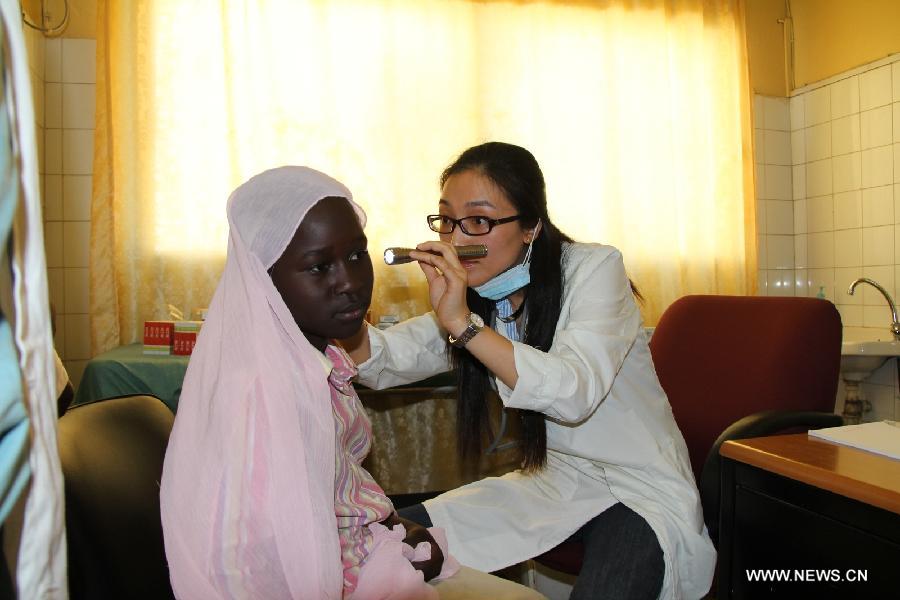 A Chinese doctor (R) examines the ear of a female patient at the Hann/Mer Medical Center in Darkar, capital of Senegal, March 31, 2013. The 14th Chinese medical team in Senegal provided free medical service and medication to local people in Dakar on March 31. (Xinhua/Wang Meng)
